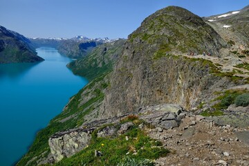 Scenic Besseggen trail in Jotunheimen, Norway - the most beautiful trekking trail in Norway. Silhouettes of hiking tourists on trail.	
