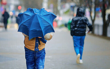Strong wind blowing, man with blue umbrella. Man holding blue umbrella during gust wind. Man...