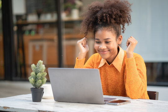 Young African American woman having conference video call using laptop talking to coworker online audience sitting at office desk in the evening. Consultation, webinar, tutoring on the internet.
