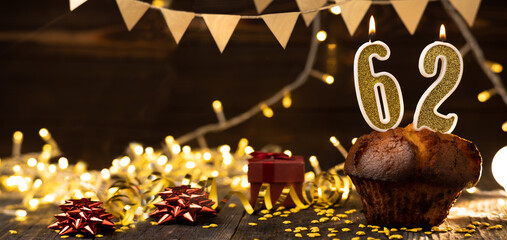 Number 62 golden festive burning candles in a cake, wooden holiday background. sixty-two years of birth. the concept of celebrating a birthday, anniversary, holiday. Banner.