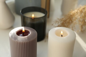 Fototapeta na wymiar Different burning candles on white table. Decoration element
