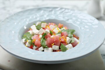 Delicious salad with watermelon, arugula and feta cheese served on white marble table, closeup