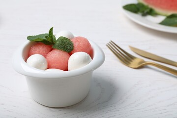 Delicious salad with watermelon balls, mint and mozzarella served on white wooden table, closeup