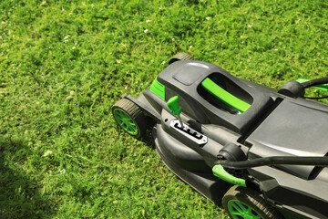 Lawn mower on green grass in garden. Space for text