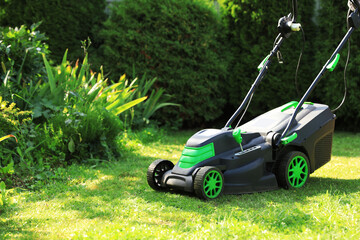 Fototapeta na wymiar Lawn mower on green grass in garden