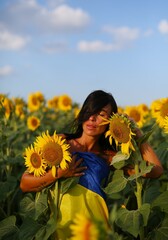 A beautiful Ukrainian girl, standing in a field of sunflowers, wrapped in her national flag, the flag of Ukraine. No war in Ukraine