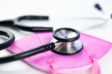 Close up stethoscope and pink face mask for medical women's day in science. Health and medicine concept. Coronavirus and breast cancer concept. White background with copy space.