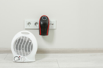 Modern electric compact and fan heaters indoors, space for text