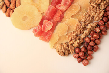 Different tasty nuts and dried fruits on beige background, flat lay. Space for text