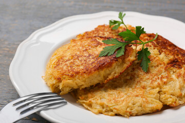 Tasty parsnip cutlets with parsley on grey wooden table, closeup