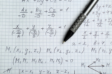 Sheet of paper with different mathematical formulas and pen, top view