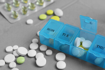 Weekly pill box with medicaments on grey table, closeup