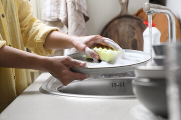 Woman washing plate in kitchen sink, closeup