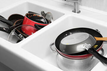 Stacks of dirty kitchenware in white sink