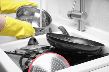 Obraz premium Woman washing pot in kitchen sink, focus on dirty kitchenware
