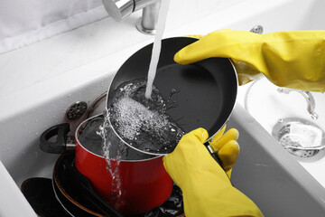 Woman washing frying pan in kitchen sink, closeup