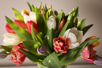 Beautiful bouquet of colorful tulips on beige background, closeup