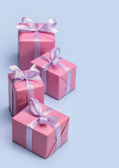 Four Christmas gift boxes with ribbons and bows. Blue background, copy space, vertical shot.