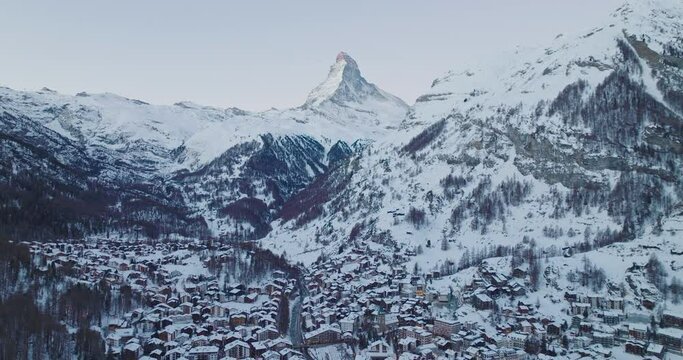 Aerial drone shot of Zermatt city Valley famous travel ski resort and iconic Matterhorn peak at dawn in the swiss alps, Switzerland. The snow covered village and church in Canton Valais in winter.
