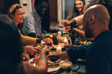 multiethnic people sitting together in a joyful night at home or restaurant eating vegetarian food and drinking wine celebrating friendship and family life