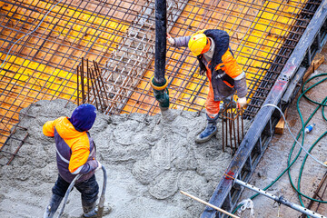 Workers are pouring structural concrete at a construction site
