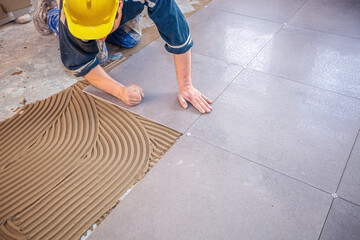 Tiler lays stoneware tiles on the floor