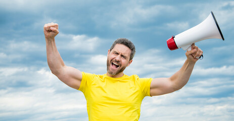 man in yellow shirt with loudhailer on sky background