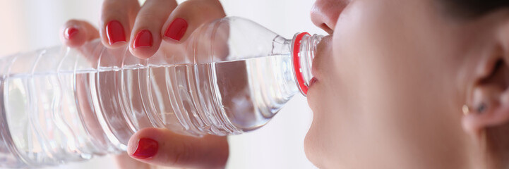 Young woman drinks bottle of mineral clear water