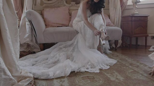 Young bride strapping up her high heels. Victorian, vintage, antique style wedding venue. 4K 60 FPS. Email willneathery yahoo.com to purchase entire wedding event at wholesale price.