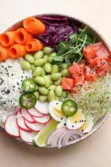 Delicious poke bowl with quail eggs, fish and edamame beans on light table, top view