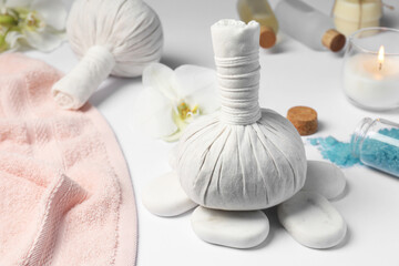 Fototapeta na wymiar Herbal massage bags, spa stones, sea salt and towel on white table