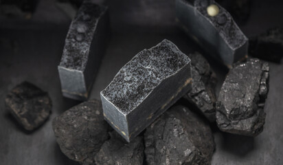 Natural charcoal soap on real coals on a dark background. Concept of making and using organic eco soap and cosmetics