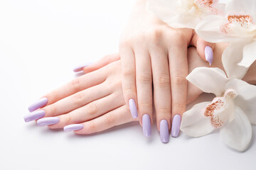 Obraz na płótnie Canvas Girl's hands with delicate purple manicure and orchid flowers