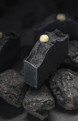 Natural charcoal soap on real coals on a black background. Concept of making and using organic eco soap and cosmetics