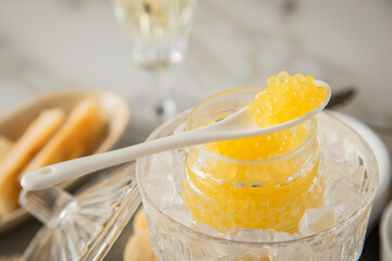 Gelber Saiblings Kaviar auf Porzellan Löffel mit Toast Brot und Champagner Sekt auf Eis, Silber...