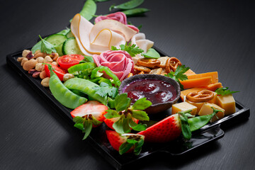 Antipasto platter cold sliced ham, salami, crackers, strawberries, vegetables and cheese platter on...
