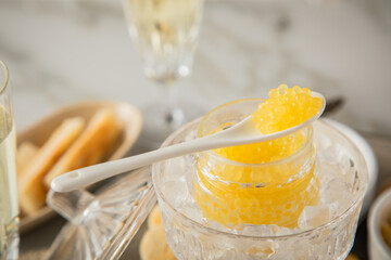 Gelber Saiblings Kaviar auf Porzellan Löffel mit Toast Brot und Champagner Sekt auf Eis, Silber...