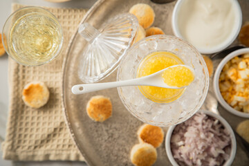 Gelber Saiblings Kaviar auf Eis in Glas Schale mit Porzellan Löffel, gekochte Eier Würfel,...