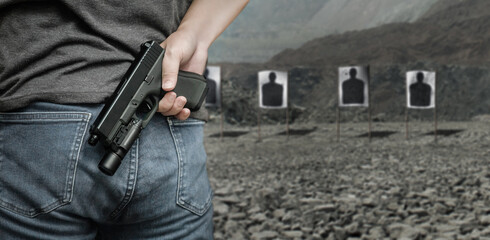 A man pulls out a gun rear view at outdoor academy shooting range