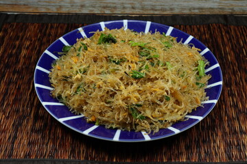 Traditional fried and stirred fresh vermicelli or glass noodle mixed with celery and tofu serving on the plate. Famous vegetarian menu in Asia restaurant. 