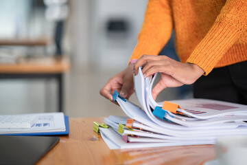 Close-up hand of businesswoman arranging documents on her desk.