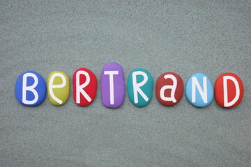 Bertrand, french masculine given name composed with multi colored stone letters over green sand