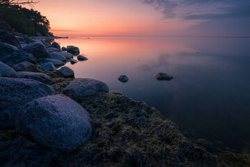 wonderful colorful sunset on a calm sea with a rocky shore