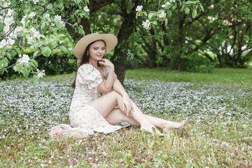 An attractive long-haired woman walks in the spring in the park of blooming apple trees.