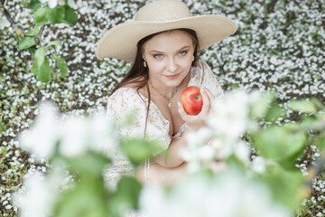 An attractive long-haired woman walks in the spring in the park of blooming apple trees.