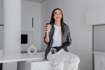 Attractive brunette caucasian girl in grey shirt, white pants drinks coffee, learns how to use...