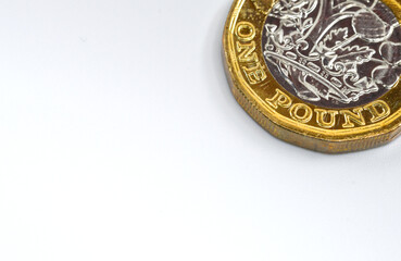 Corner of a British One Pound coin isolated on a plain white background. Copy space.