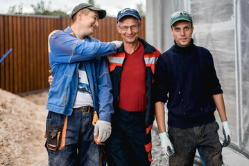 business, building, teamwork and people concept - group of smiling builders outdoors