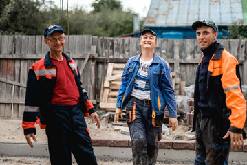 business, building, teamwork and people concept - group of smiling builders outdoors