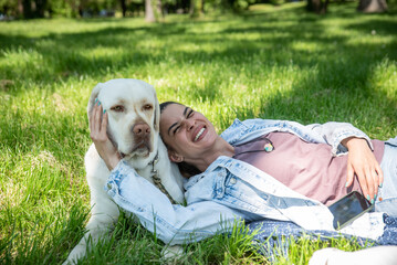 Young woman adopt young dog Labrador Retriever from animal rescue shelter center and gave him love and friendship. Female animal lover spending time with her puppy in the park.